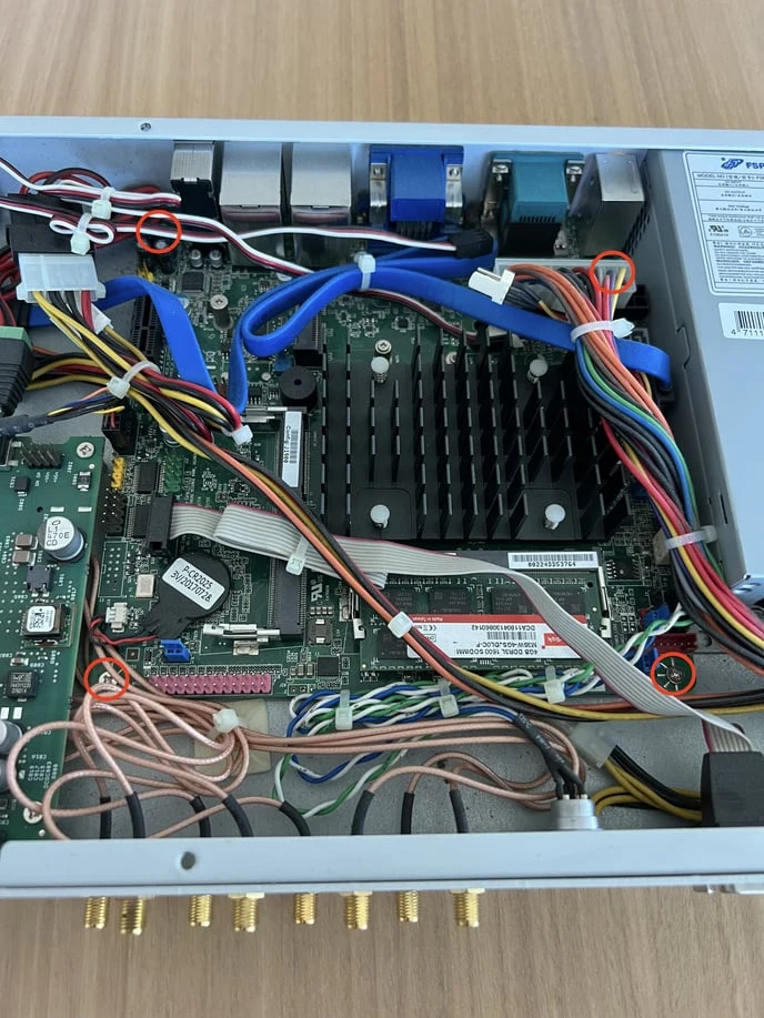 The inside of a white robot, the four corner screws of the motherboard circled in red